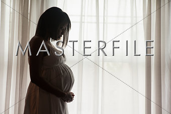 Pregnant African-American woman standing by the window