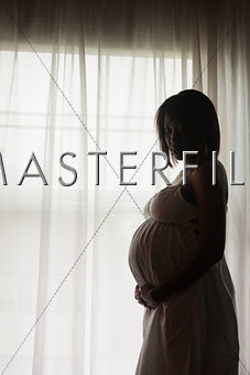 Pregnant African American woman standing by the window