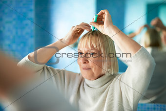 senior woman checking hairline for hair loss