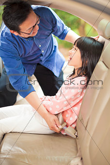 father help daughter to fasten a seat belt
