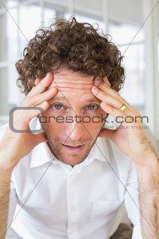 Worried man sitting with head in hands at home