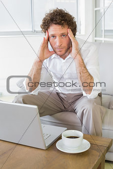 Worried well dressed man sitting with laptop at home