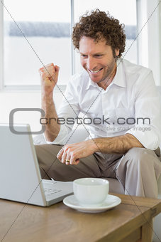 Happy young man with laptop at home