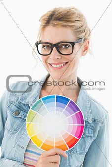 Blonde designer holding colour wheel smiling at camera
