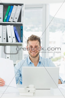 Handsome man working at his desk smiling at camera