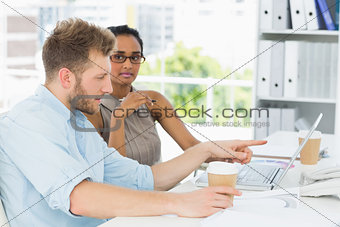 Casual business partners working together on laptop at desk