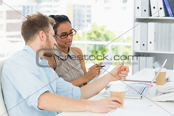 Focused business partners working together on laptop at desk