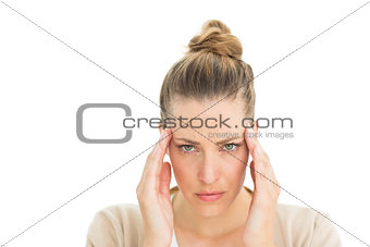 Woman with headache touching her temples looking at camera