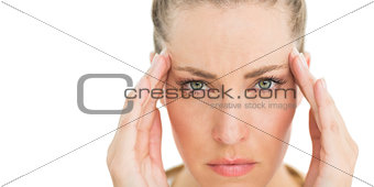 Woman with headache touching her temples frowning at camera