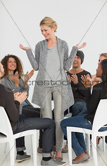 Rehab group applauding smiling woman standing up