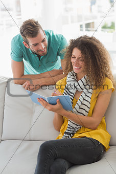 Smiling woman on the couch showing her co worker her notebook
