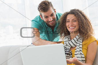 Smiling woman on the couch showing her co worker her laptop