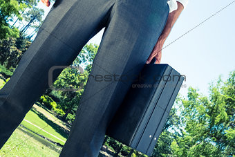 Businessman carrying briefcase at park