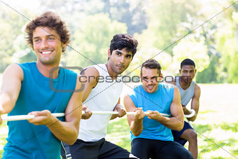Friends playing tug of war in park