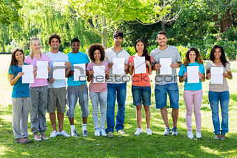 Friends holding blank papers in park