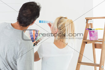 Rear view of a couple choosing color for painting a room
