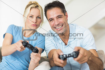 Cheerful couple playing video games in living room