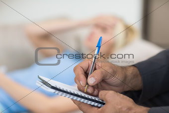 Hands writing diary with blurred woman in background