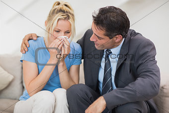 Well dresses man consoling a woman in living room