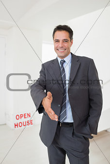 Well dressed smiling real estate agent offering handshake