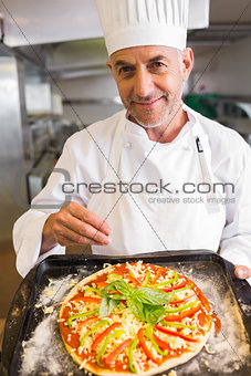 Confident male chef holding cooked food in kitchen