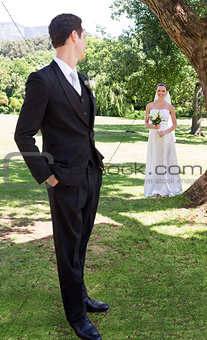 Groom looking at bride in garden