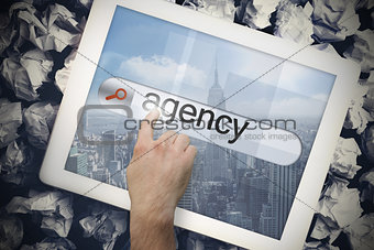 Hand touching agency on search bar on tablet screen