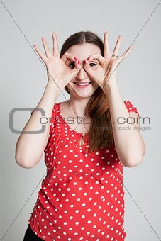 Smiling attractive woman looking through finger goggles