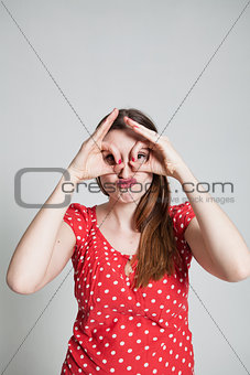 Attractive woman looking through finger goggles