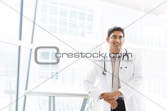 Smiling Asian Indian male medical doctor inside hospital.