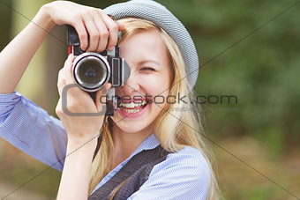 Happy young hipster taking photo with retro photo camera sitting