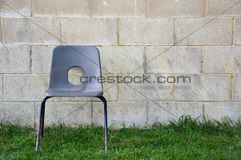 Abandoned chair in front of a concrete block wall