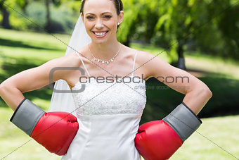 Bride wearing boxing gloves with hands on waist