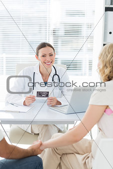 Confident female doctor with expectant couple