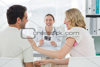 Expectant couple with doctor in clinic