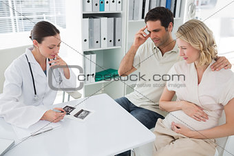 Expectant couple and doctor discussing over reports