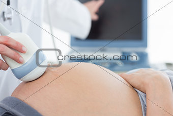 Doctor using ultrasound scanner on pregnant woman