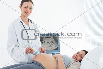 Smiling doctor performing ultrasound on pregnant woman