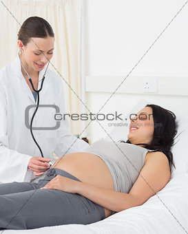 Doctor examining stomach of pregnant woman