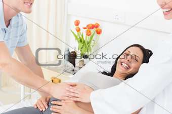 Happy pregnant woman with man and doctor