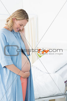 Smiling pregnant woman looking at belly