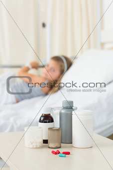 Medicine bottles on table with girl in hospital