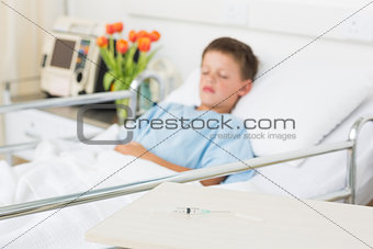 Syringe on table with boy in hospital ward