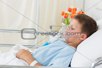 Sick boy wearing oxygen mask in hospital