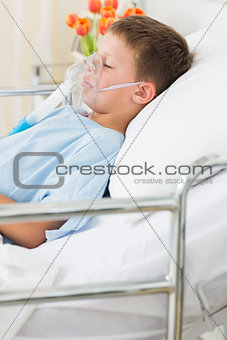 Boy wearing oxygen mask in bed