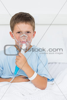 Boy wearing oxygen mask in hospital ward
