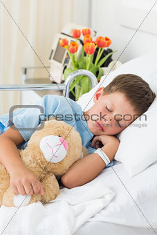 Boy with teddy bear sleeping in hospital