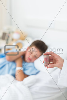 Doctor holding pill bottle with boy in ward