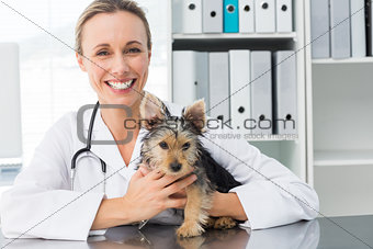 Happy female veterinarian holding puppy