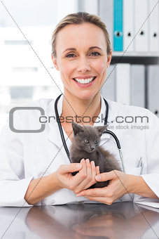 Happy female vet holding kitten